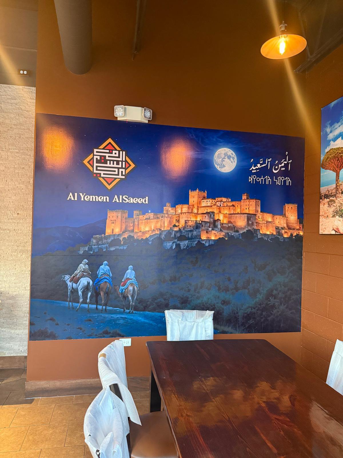 Al Yemen Al Saeed dining area with a large blue cultural wall mural and restaurant branding