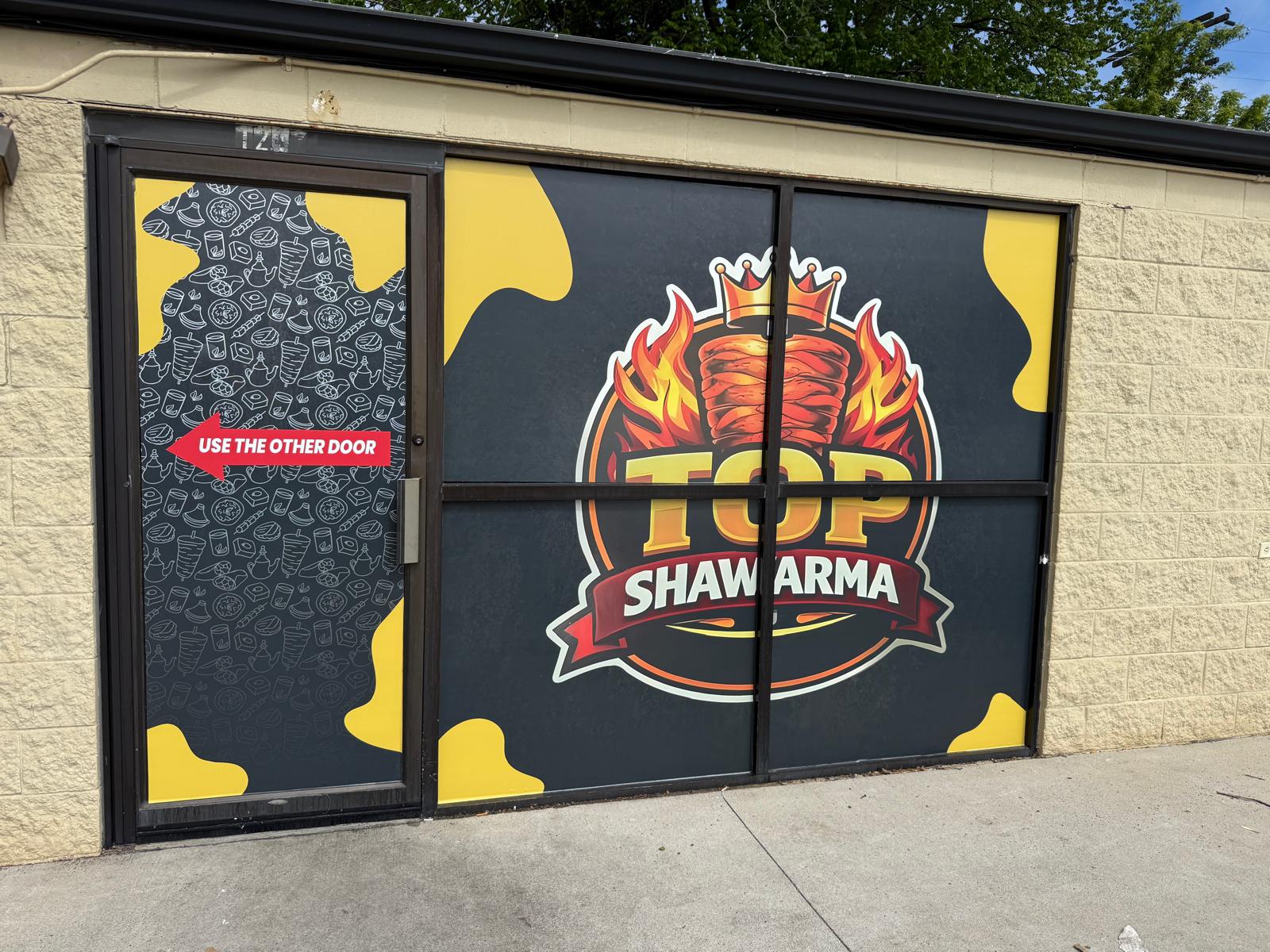 Top Shawarma storefront with large custom branded window graphics